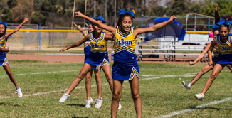 Picture of Youth Cheerleaders doing jumping jacks on football field.