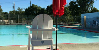 Picture of empty lifegaurd chair at public pool.